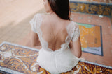 Mariée avec une robe en dentelle ouverte dans le dos accessoirisé d'un collier de dos à fleur dorée