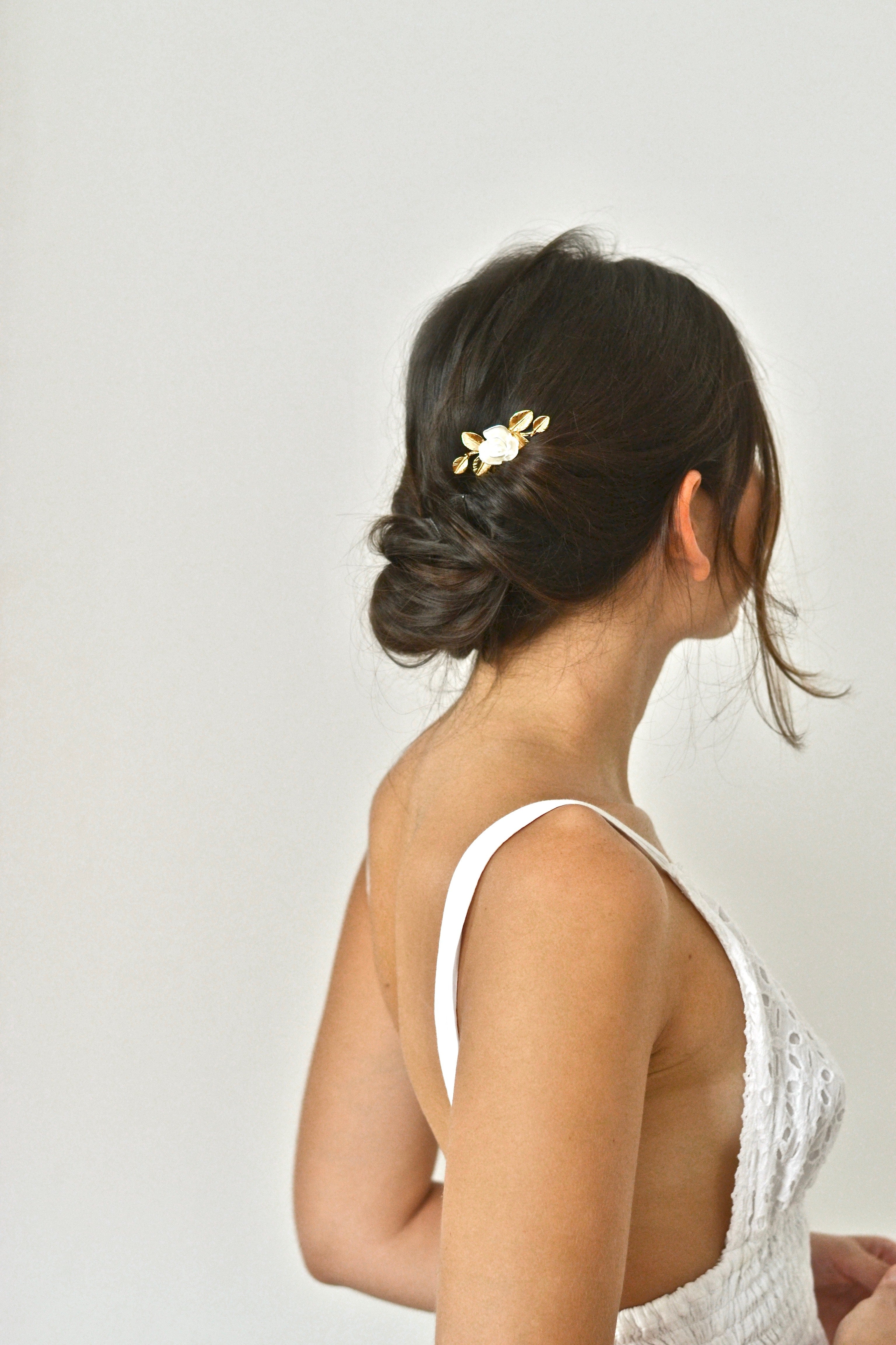 mariée en robe blanche en dentelle coiffée avec un chignon et un pic de cheveux en fleur blanche