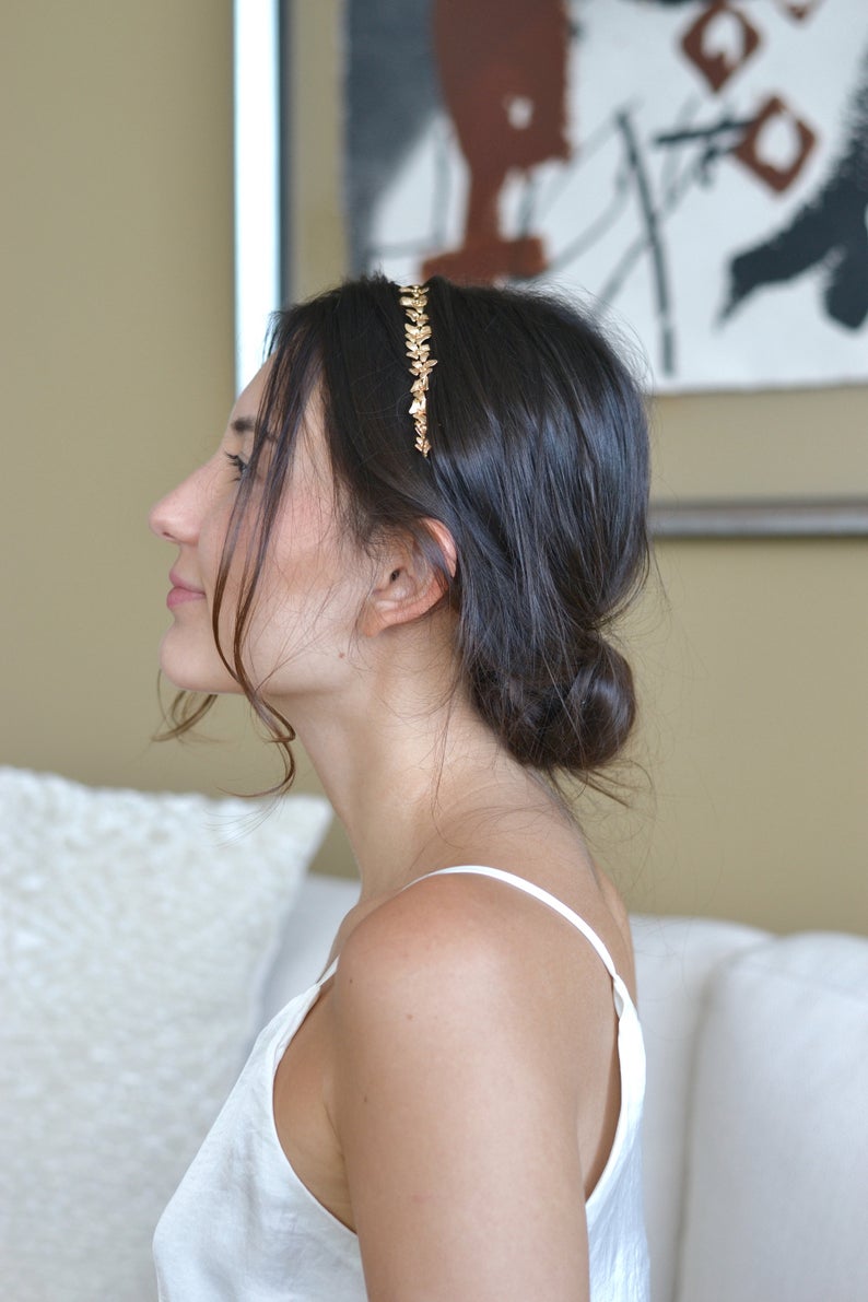 coiffure de mariée avec un chignon bas et des fleurs en or