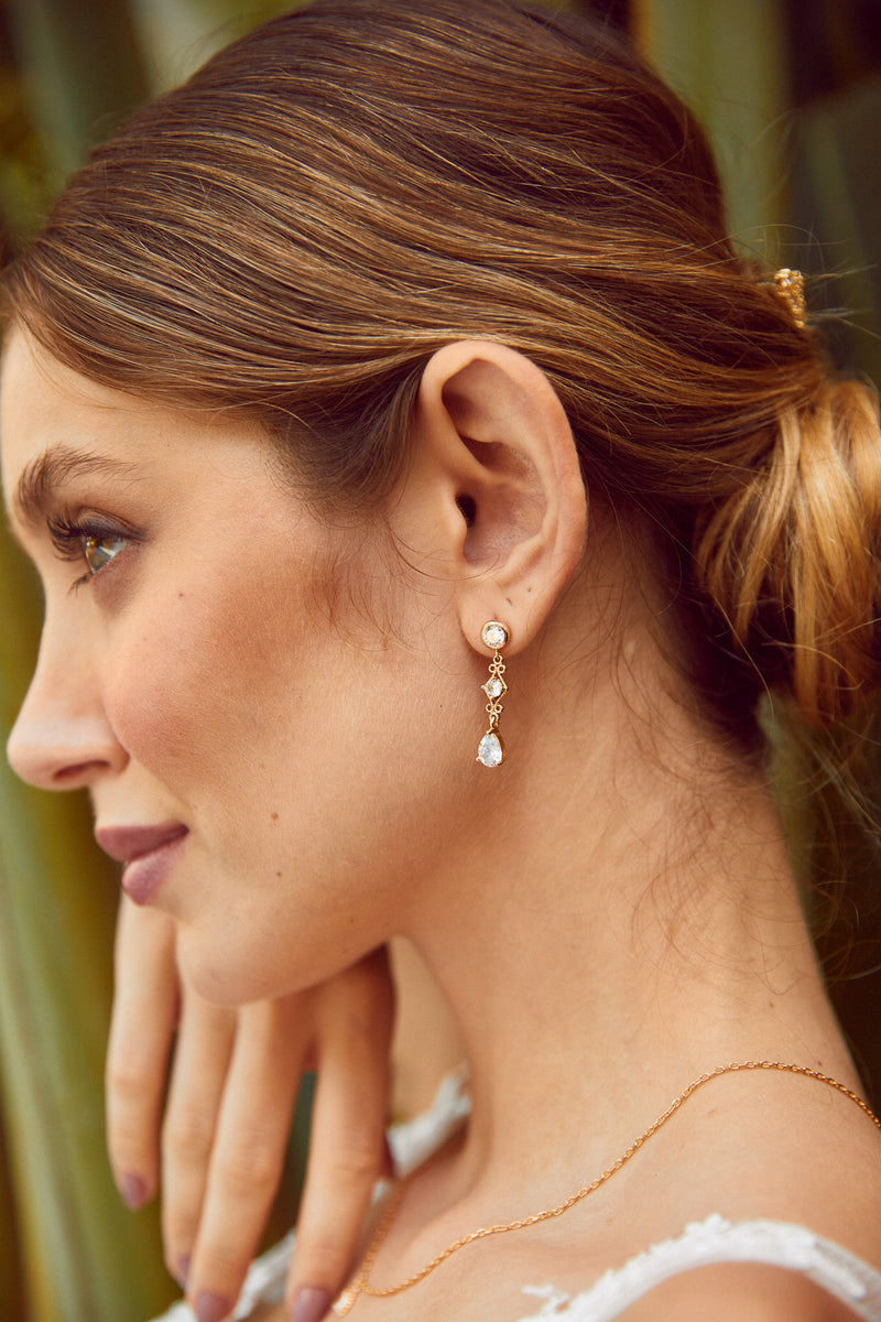 femme de profile portant des boucles d'oreilles vintage avec des cristaux transparent