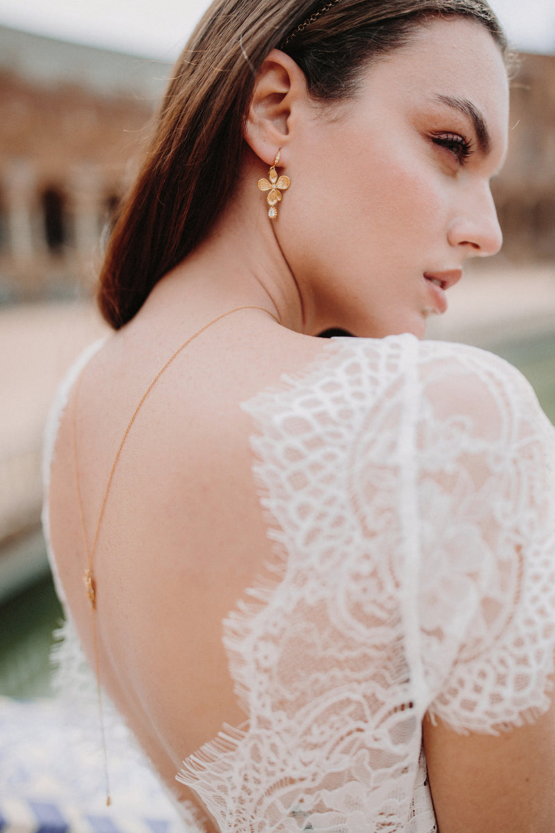 boucles d'oreilles mariage en or veille en forme de fleurs avec un cristal avec une robe de mariée avec dentelle