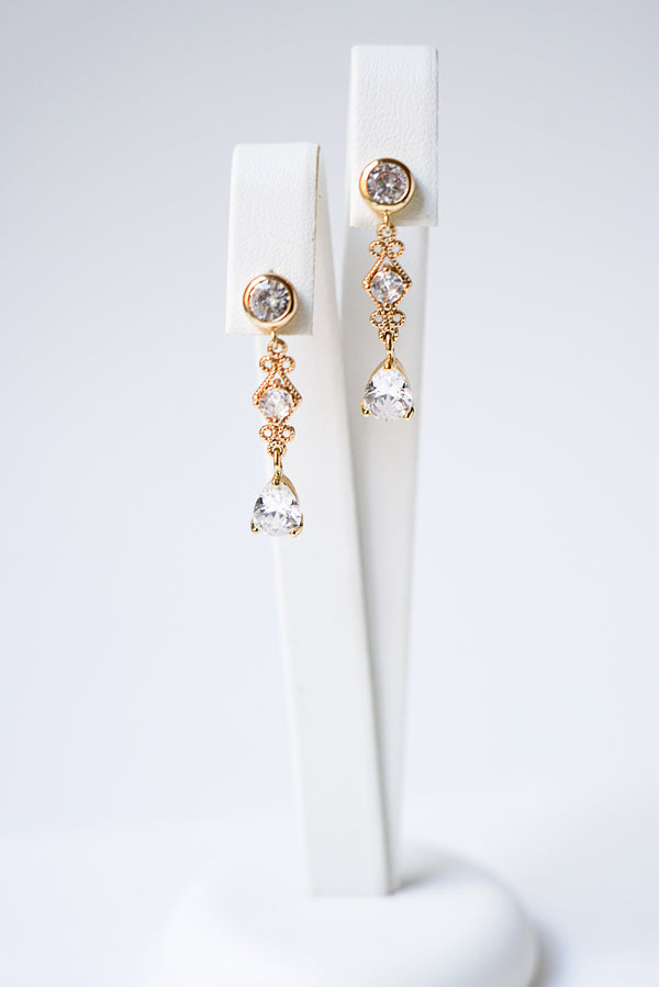 boucles d'oreilles en zircon style vintage bohème posé sur un socle à bijoux blanc