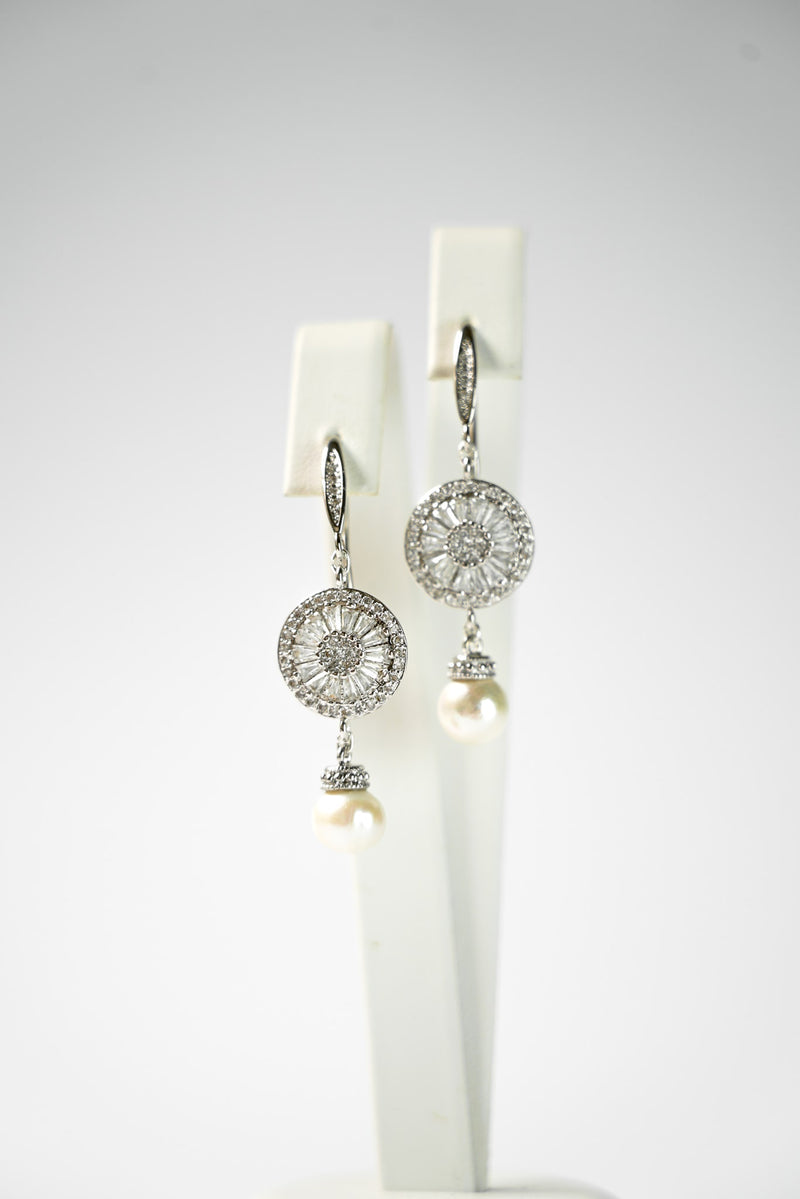 boucles d'oreilles avec une attache et un connecteur en zircon argenté et une perle naturelle sur un socle de bijou