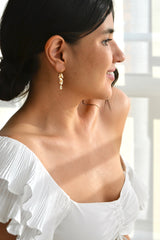 Mariée portant des boucles d'oreilles pendantes romantiques à fleur en or et cristaux