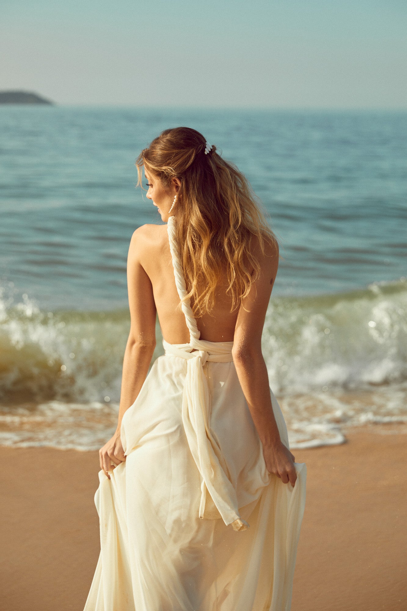 mariée sur la plage qui porte des boucles d'oreilles en perles et un peigne en nacre