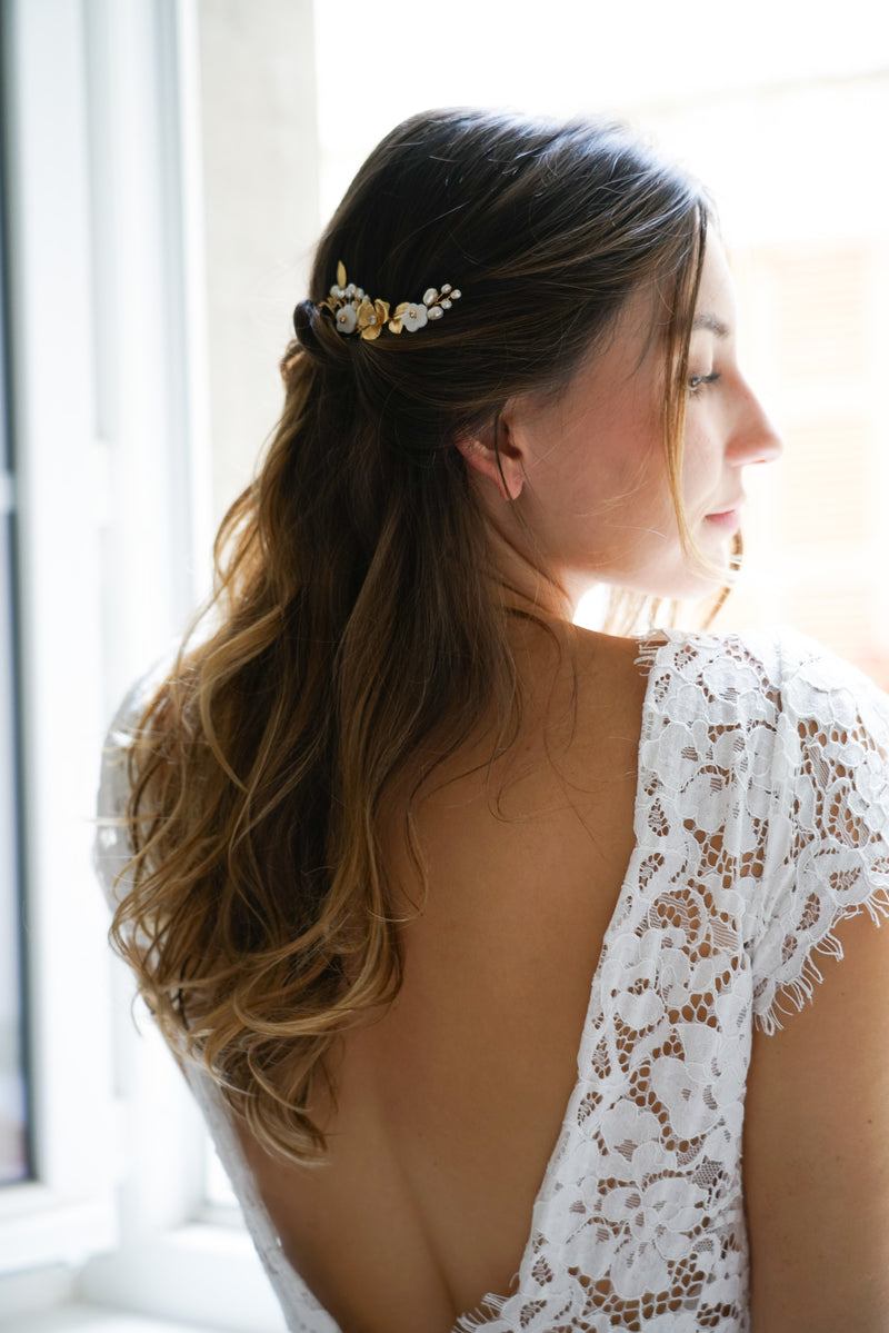 mariée de profil portant sa robe de mariée avec dentelle avec un dos nu et un pic floral dans les cheveux