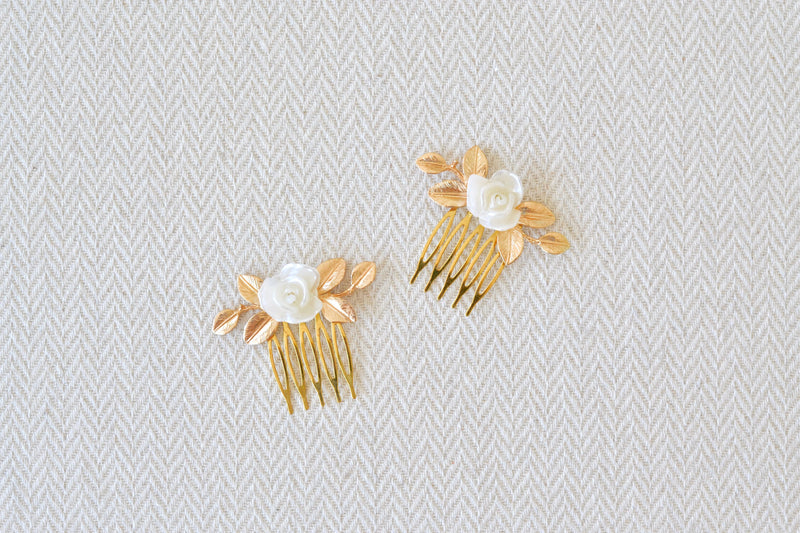 petit peigne de mariage avec une fleur blanche et des feuilles en or sur un fond blanc