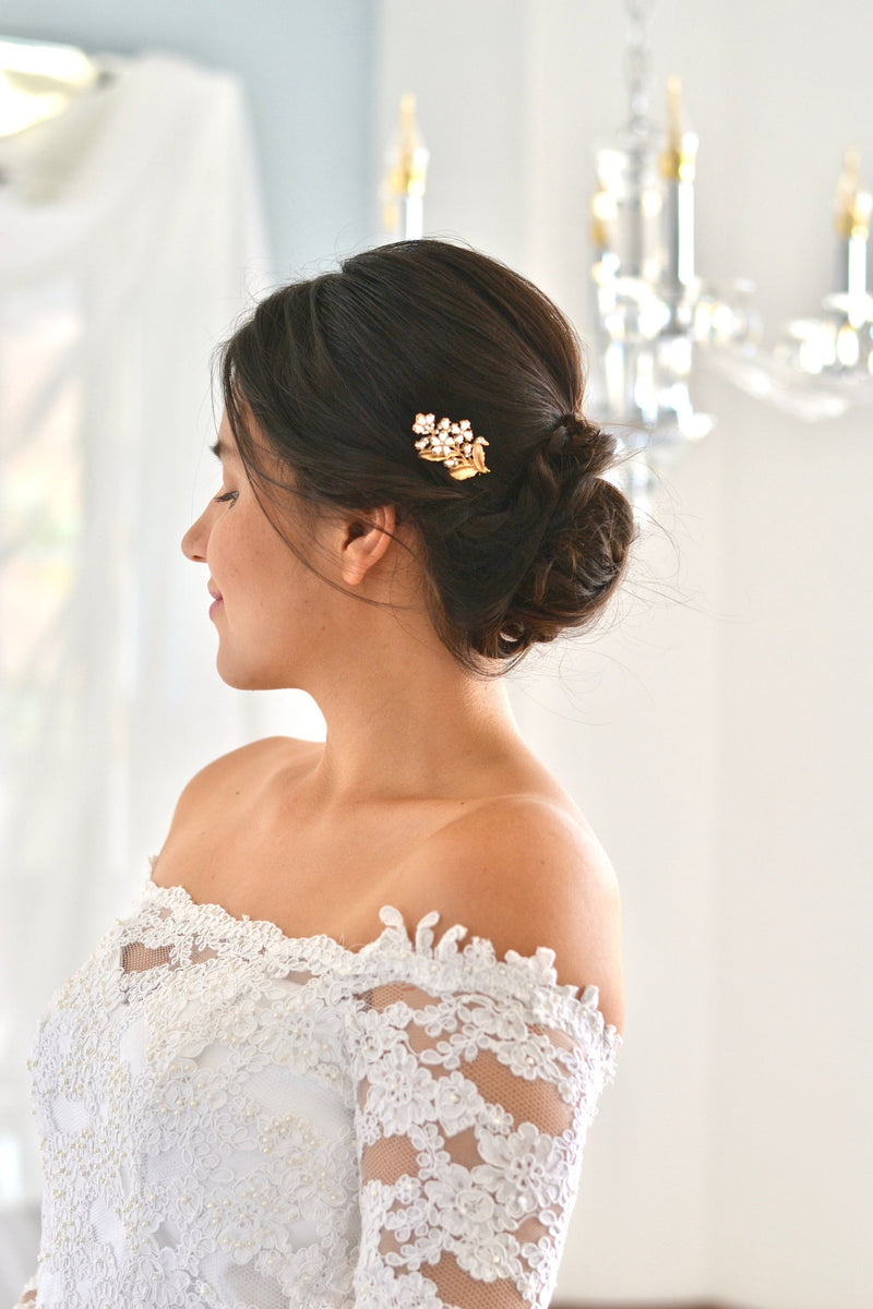 petit peigne de cheveux mariage dans le style floral romantique avec des fleurs blanche et une feuille en or porté par la mariée
