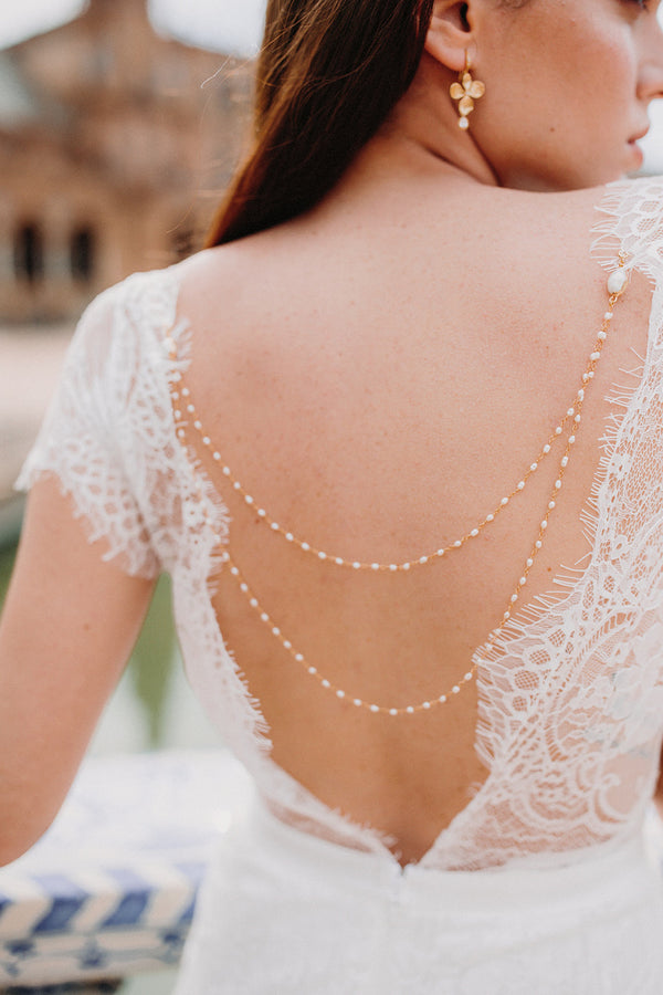 Mariée portant un bijou de robe à perles et boucles d'oreilles à flleurs en or