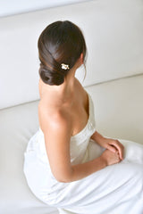 Mariée avec un chignon bas élégant portant un pic à cheveux à à perles et cristaux