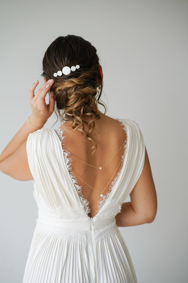 mariée coiffée pour son mariage avec un peigne en nacre et une robe blanche