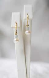 boucles d'oreilles mariage avec une perles blanches naturelles et une petite pierre naturelle bleu sur fond blanc
