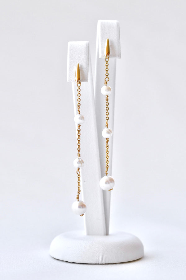 boucles d'oreilles pendantes avec 3 perles naturelles sur un socle blanc de bijou