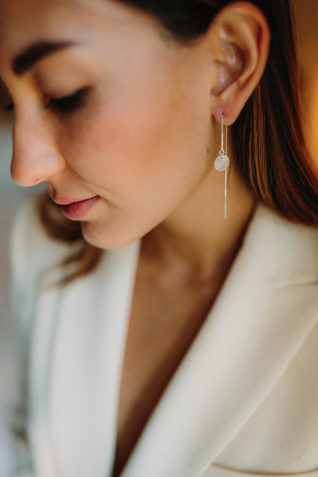 mariée portant des boucles d'oreilles avec un rond transparent et une attache en chaine argentée