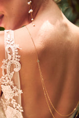 Mariée portant en collier de dos bohème fait de deux chaines dorées à cristaux et de boucles d'oreilles pendantes à perles 