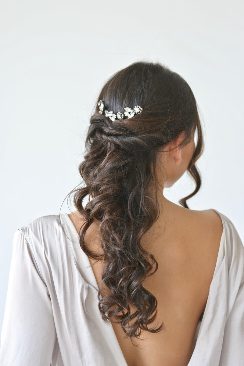 Mariée portant une vigne à cheveux florale à cristaux sur une coiffure de mariée semi attachée bouclée