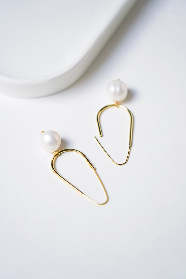 boucles d'oreilles mariage minimaliste en forme ovale avec une perle naturelle sur un fond blanc