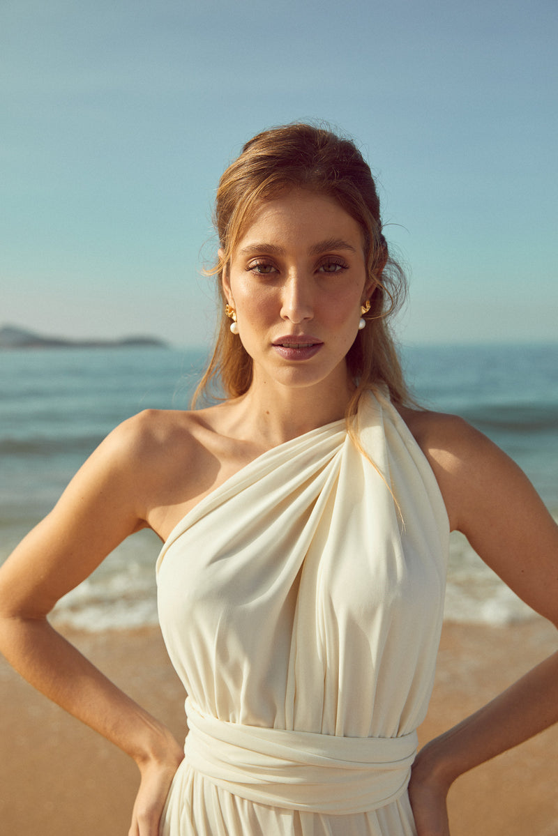 Mariée élégante sur la plage avec des boucles d'oreilles or et perles minimalistes