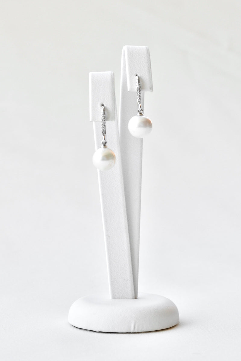boucles d'oreilles bohème avec une attache en argent et cristaux et une perle naturelle sur un socle blanc