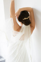 Mariée portant un long voile blanc accroché par un peigne floral et romantique