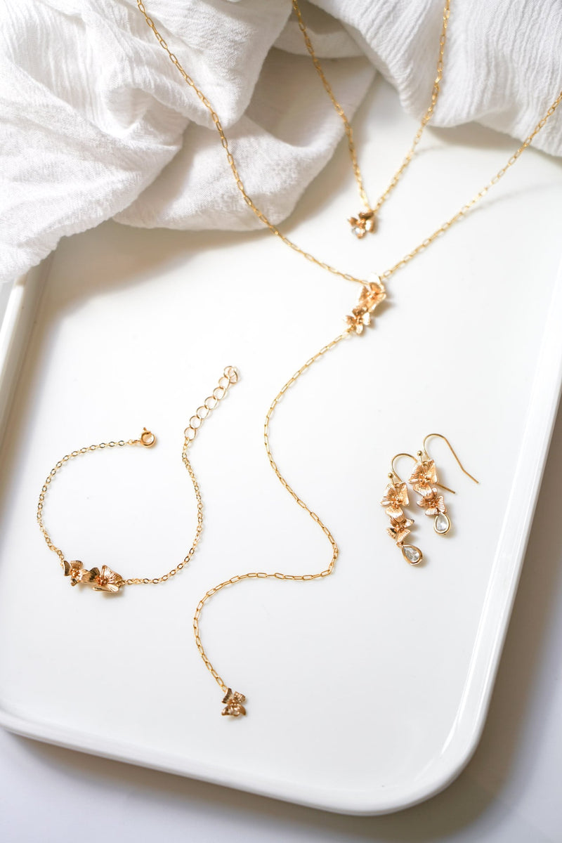 parure de bijoux en or style floral avec des cristaux sur un plateau blanc