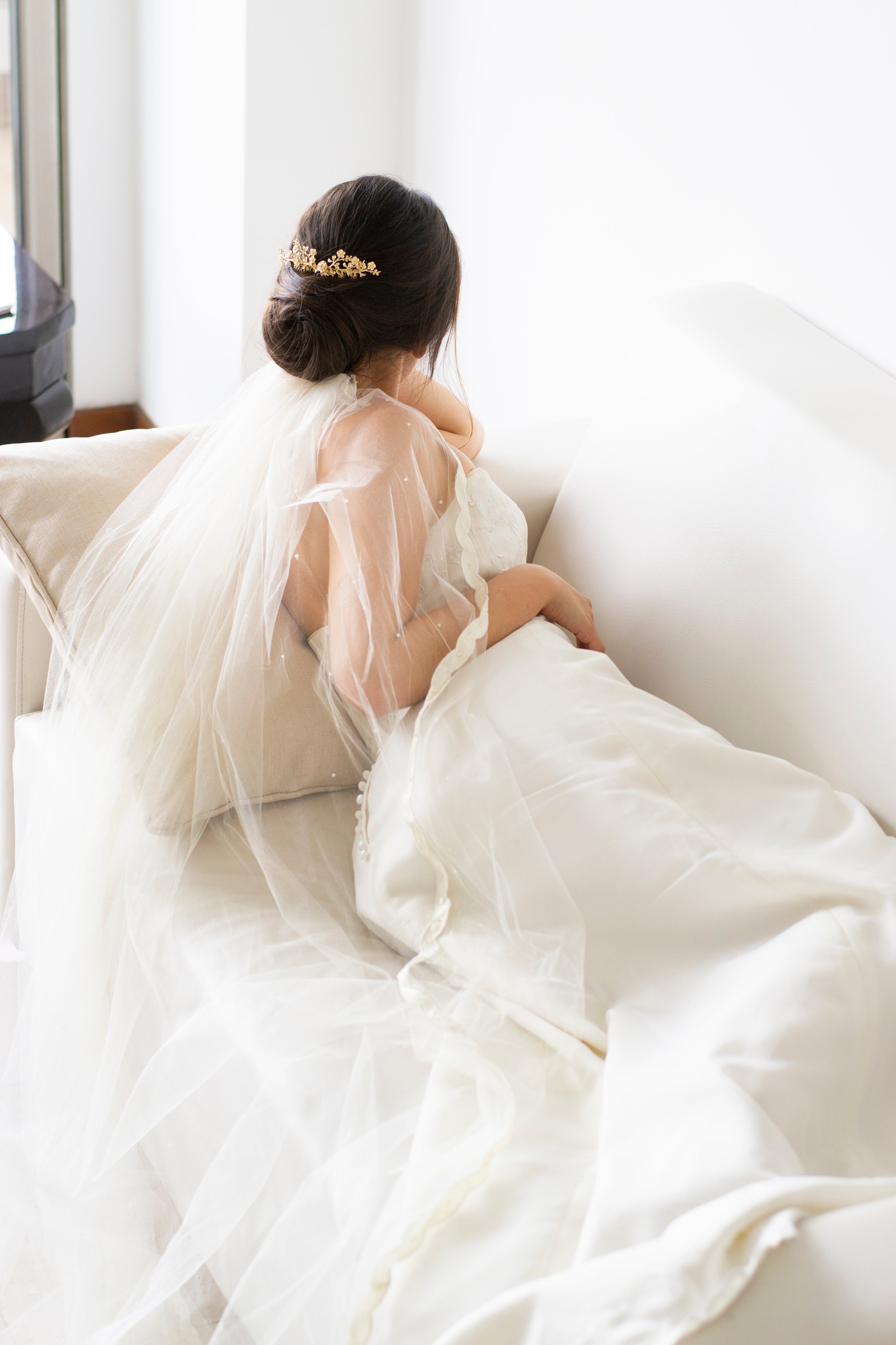 Mariée avec un long voile blanc portant un peigne à cheveux romantique et floral doré