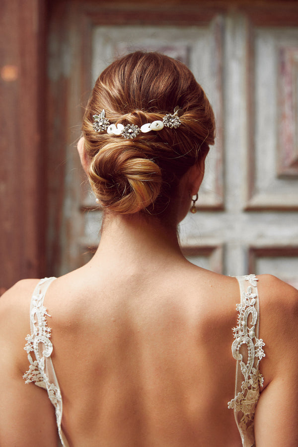 mariée coiffée avec un chignon bas et deux pic de chevaux mariage avec des perles naturelles porté par la mariée le jour j