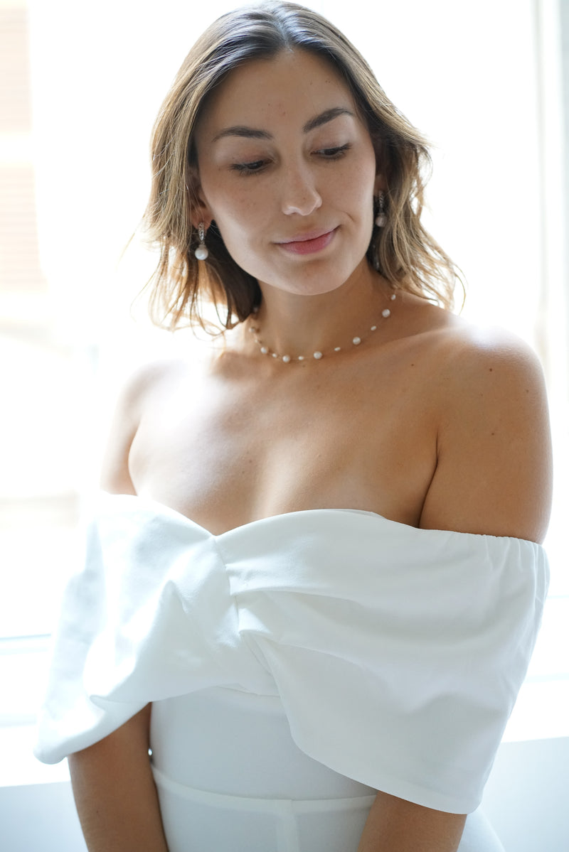 collier de mariage en perles sur un fil transparent pour mariée avec une robe bustier blanche