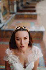 Mariée portant une sublime couronne de mariage florale dorée sur un banc en mosaïque