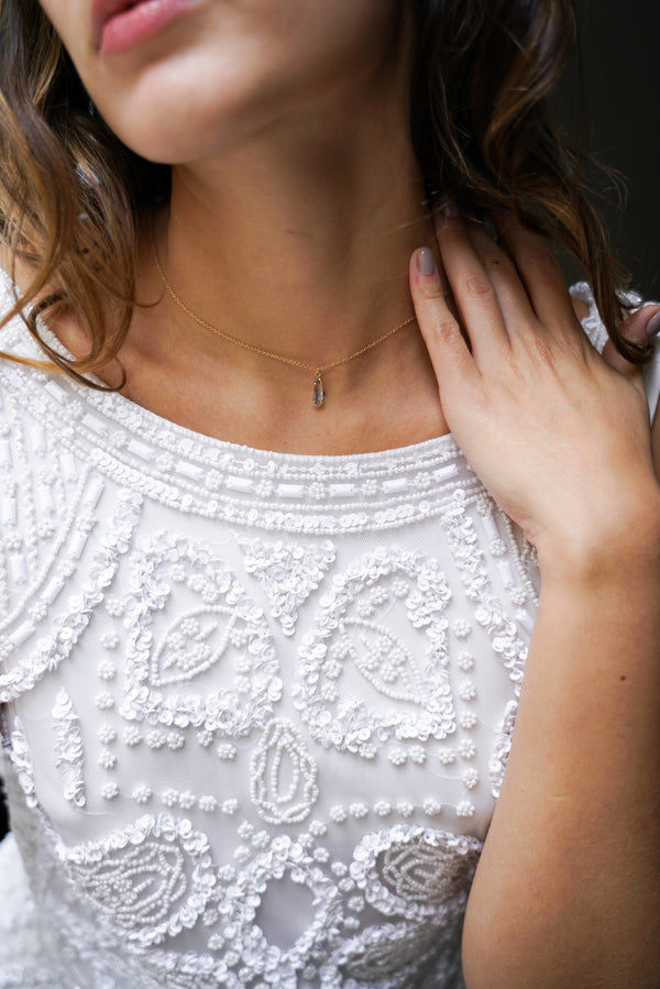 Mariée portant collier minimaliste chaine en or avec une pierre bleue claire