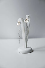 Boucles d'oreilles pendantes en argent fait à la main avec une fleur pour le centre de la boucle et une blanche de feuilles en pendentif