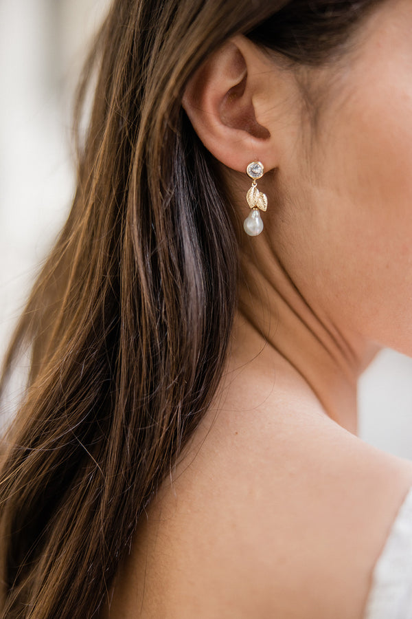 boucles d'oreilles bohème avec un zircon, un feuille en or et une perle naturelle portée sur une mariée avec les cheveux détachés