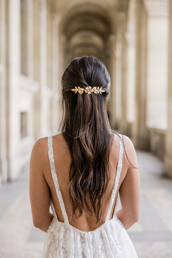 mariée prise en photo de dos avec les cheveux détachés en demi queue avec une barrette en or veille style floral vintage