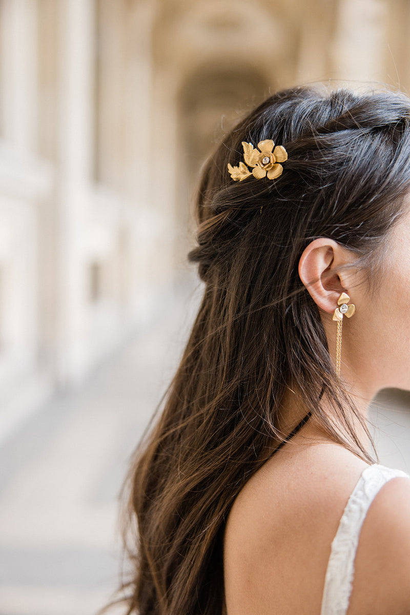 Mariée portant des boucles d'oreilles à fleurs dorées et pic à cheveux assorti romantique