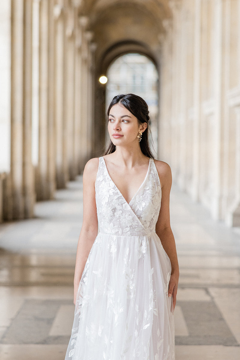 mariée en robe blanche à dentelle à Paris avec des boucles d'oreilles en perle