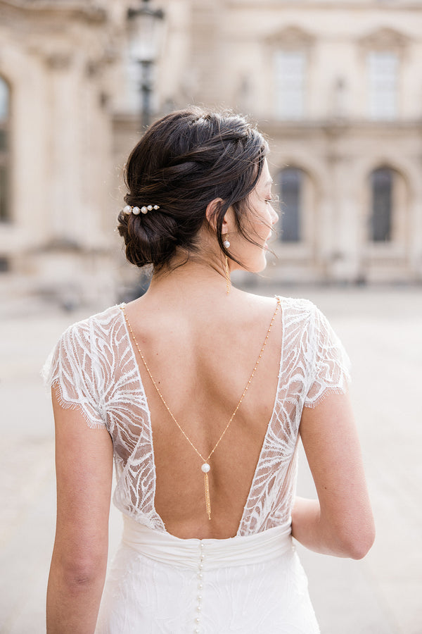 Mariée élégante et minimaliste portant un bijou de robe en chaine doré, perle naturelle et pompom de chaines