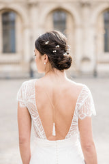 Parure de bijoux de mariée à perles blanches avec collier de dos en pompom de perles, boucles d'oreilles à perle et pics à cheveux perlées porté par une mariée au style élégant