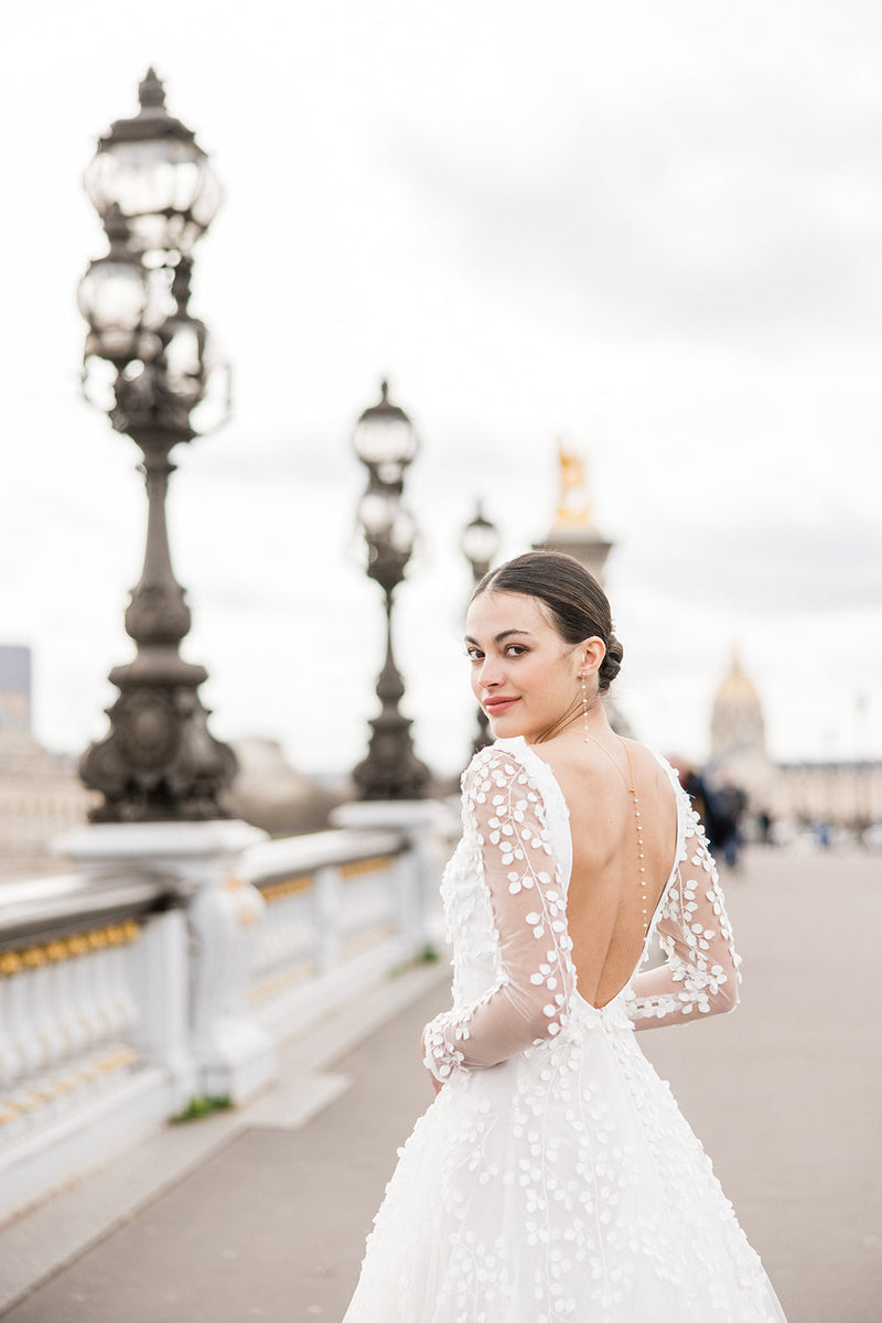 parure de bijoux en perles naturelles portés par une mariée à Paris de dos qui regarde la caméra