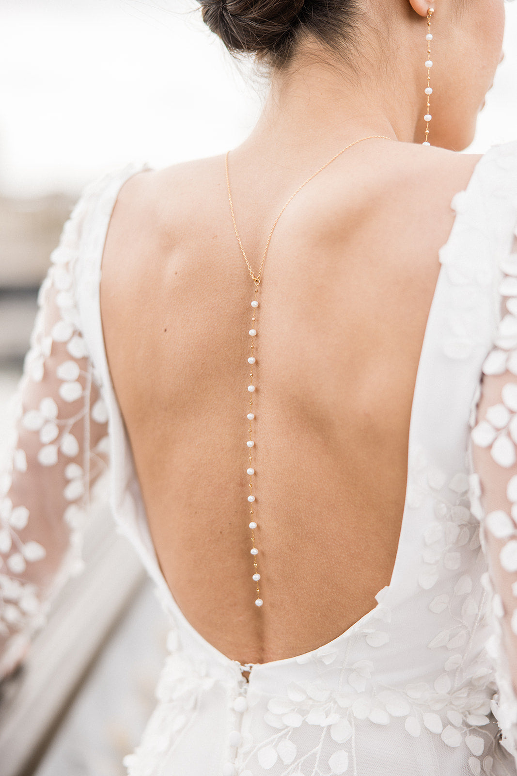 dos d'une mariée portant un collier de dos en perles naturelles 