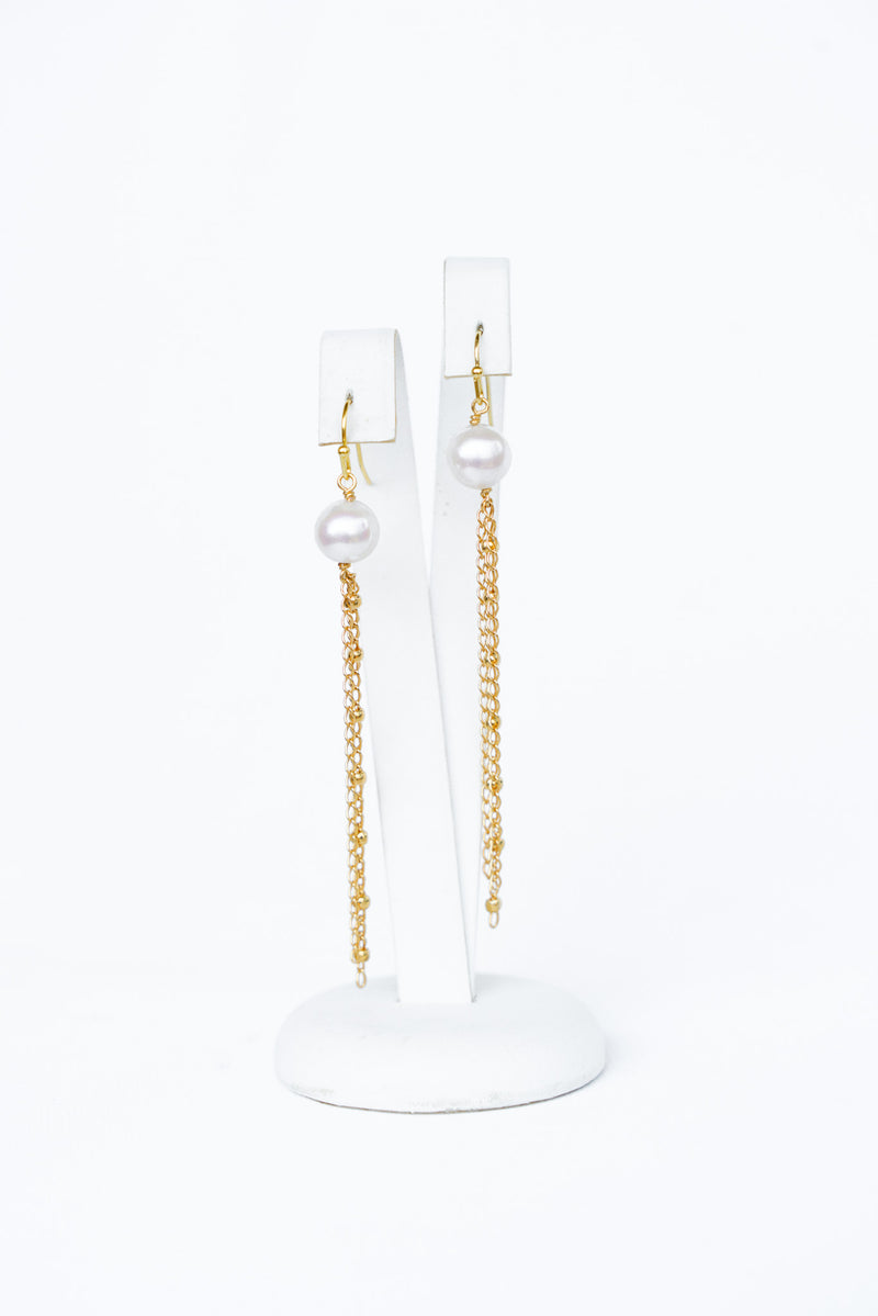 Boucles d'oreilles pendantes faites d'une perle naturelle de laquelle pend des chaines dorées