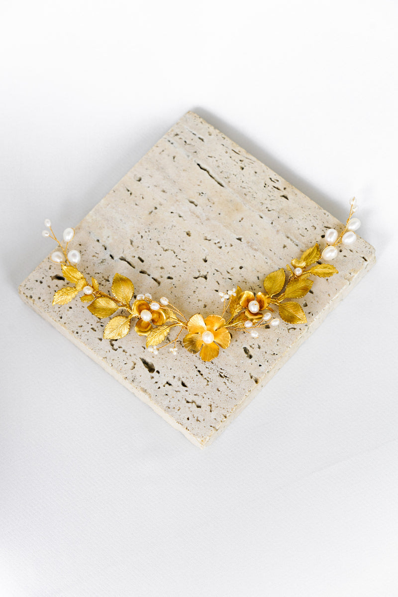 peigne de cheveux pour mariage avec une fleur or or veilli et des feuillages accompagnés de perles naturelles sur un fond blanc