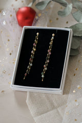 Boucles d'oreilles pendantes avec pierres naturelles colorées dans un décor de Noël