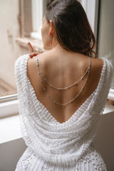 mariée portant un collier de dos en argent avec 2 étages de chaines dans le style céleste et moderne et des boucles d'oreilles assorties