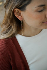 Femme portant des boucles d'oreilles pendantes avec des pierres naturelles colorées