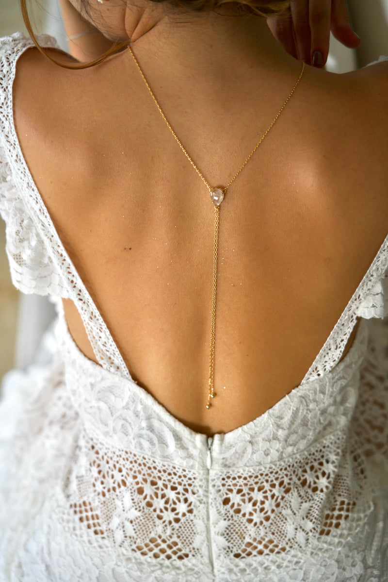 collier de dos bohème pour mariage avec un cristaux et une chaine en or pendent sur le dos de la mariée avec un grand décolletés de dos