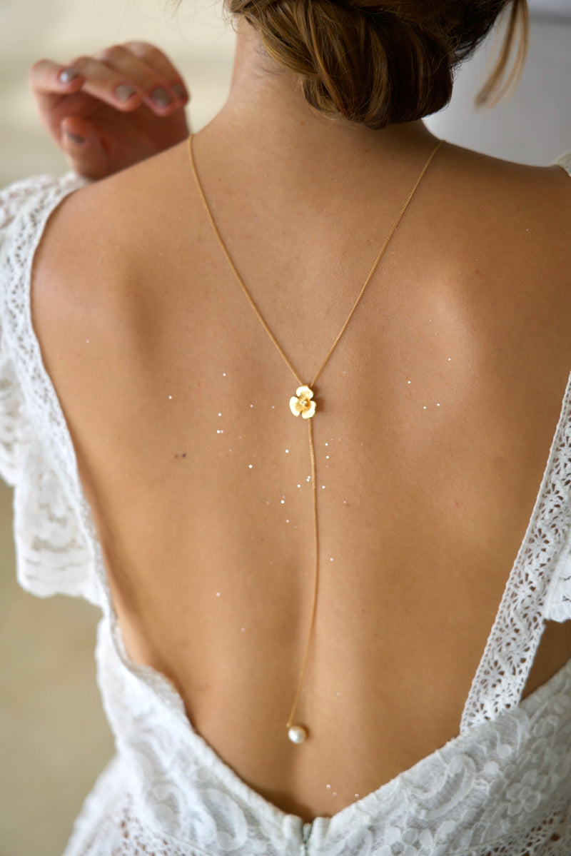 Mariée portant un collier de dos à fleur doré et perle naturelle