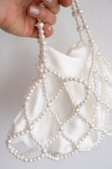 Main tenant un sac de mariage blanc malléable en perles blanches et tissu en satin chic et élégant