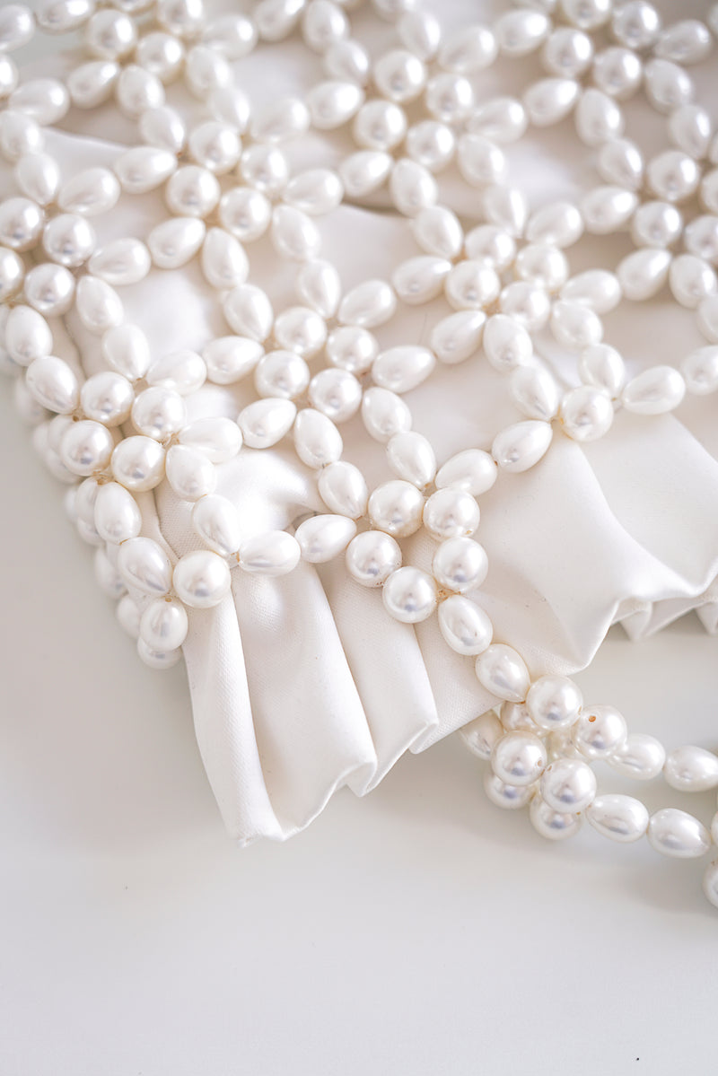 Détail d'un sac de mariée à perles blanches et tissu en satin blanc