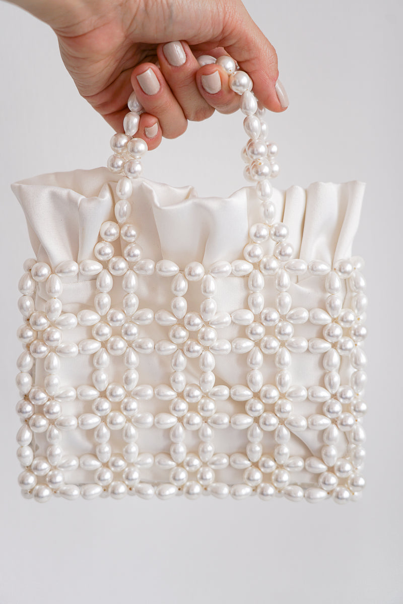Main tenant un sac de mariée blanc rectangulaire à perles et tissu en satin blanc