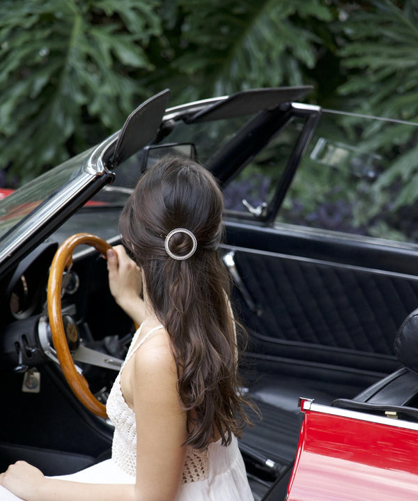 Femme au volant d'une voiture rouge avec barrette à cheveux argent ronde torsadée